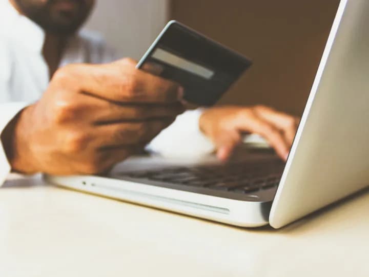 Permettez à vos clients de commander et de payer en ligne Une personne effectue un achat en ligne, carte bancaire en main devant son ordinateur portable